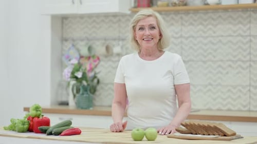 Blonde woman smiling standing at kitchen table