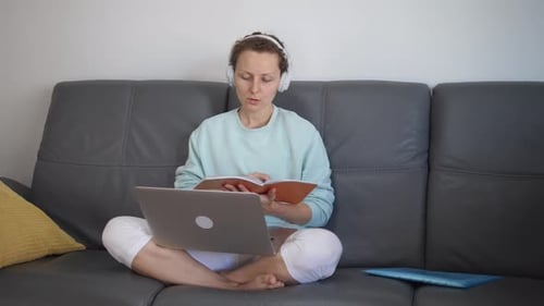 Woman Studies With Laptop and Headphones on Couch