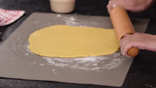 Hands Rolling Dough with Pin on Counter