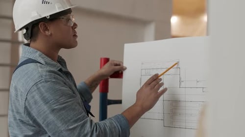 Mixed-Race Female Architect Checking Blueprint