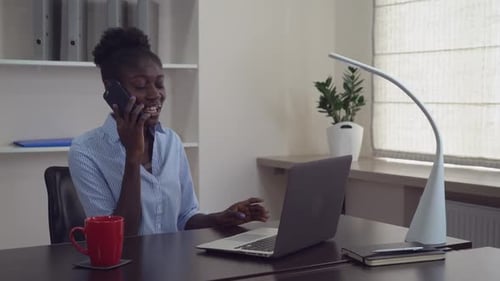 Professional Woman Working at Desk Talking on Phone