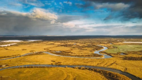Luftaufnahme der trockenen Wiese und der teilweise gefrorenen Flusslandschaft an sonnigen Herbsttagen. Ansicht von oben