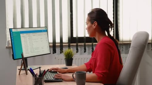 Woman Typing at Computer in Bright Office