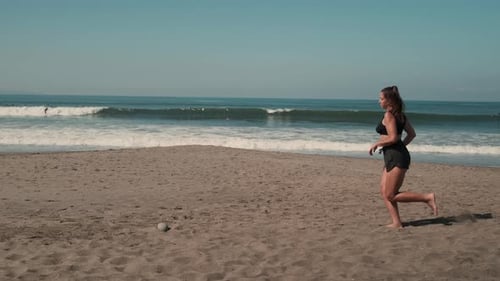 Beautiful Woman is Jogging Along Sandy Ocean Shore