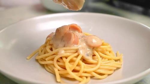 Close-up shot of hand holding a ladle pouring carbonara mushroom sauces