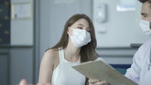 Doctor Discusses Medical Chart With Patient in Office