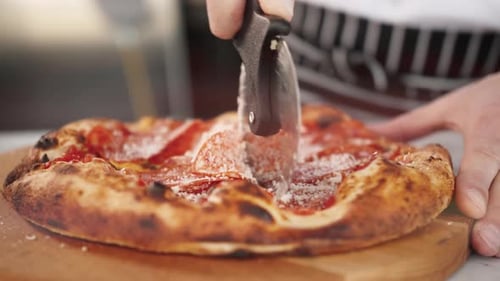 Cutting Pepperoni Pizza on Wooden Board in Kitchen