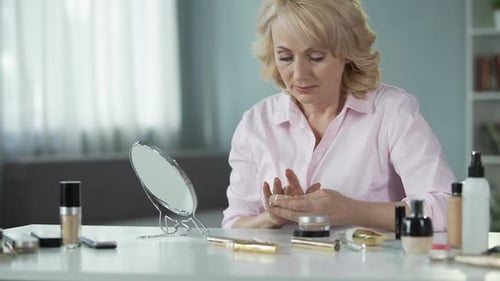 Seniorin verwendet viel teures Make-up und versteckt altersbedingte Hautveränderungen