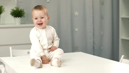 Smiling Baby Sitting on Table in Bright Room