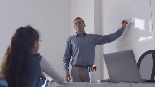 Teacher Writing on Whiteboard Explaining Lesson to Student