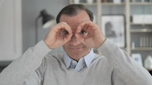 Man Makes Binocular Shape With Hands Near Eyes