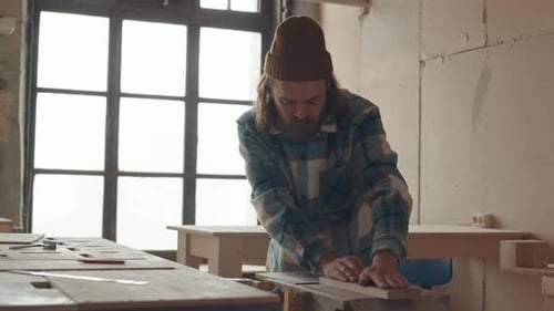 Man Working With Wood in a Bright Workshop