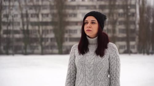 Woman Stands in Snowy Urban Winter Landscape