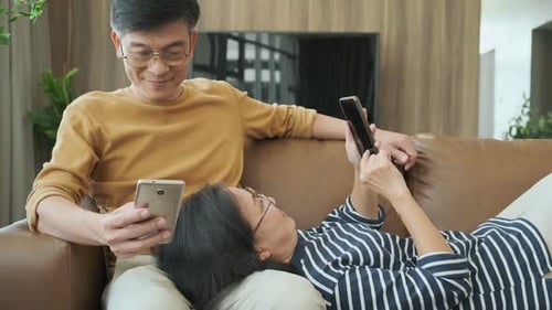 Mature Couple Relaxing on Sofa with Smartphones