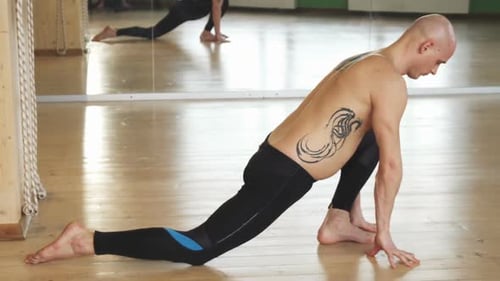 Junger Mann ohne Hemd praktiziert Yoga drinnen