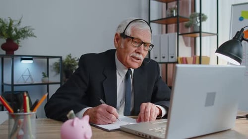 Senior Businessman Wear Wireless Headset Making Conference Video Call on Laptop Call Center Agent