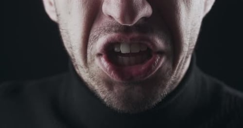 Closeup of Aggressive Man's Mouth Screams and Threatens with Violence