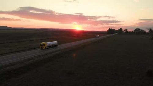 Aerial shot: vehicles, trucks and cars driving by road.