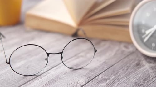 Close-up of Glasses with Open Book on Desk