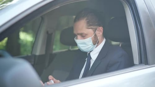Man Applies Hand Sanitizer in Car Wearing Face Mask