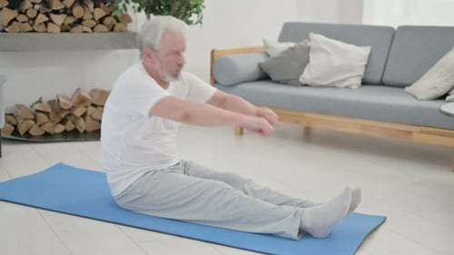 Senior Man Stretching on Yoga Mat at Home