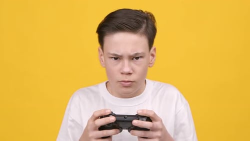 Teenager spielt Videospiel und hält Gamepad-Controller auf gelbem Hintergrund