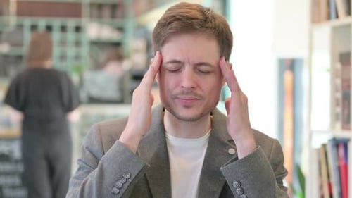 Young Adult Massaging Head Due to Headache Indoors