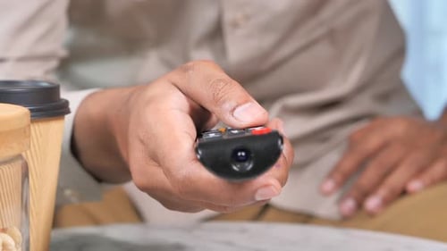 Junger Mann sitzt mit TV-Fernbedienung auf dem Sofa
