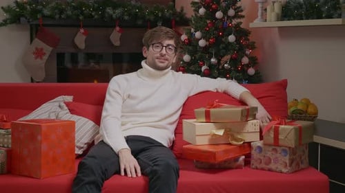 Young Man with Christmas Gifts on Red Couch