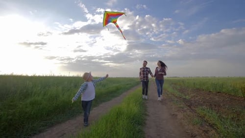 Family Runs Together Flying Kite in Rural Field