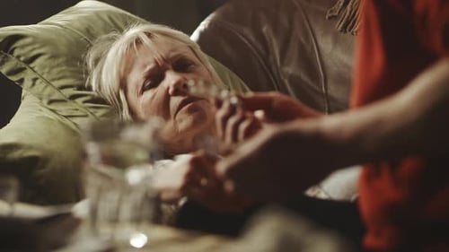 Man Gives Senior Woman Medication and Water