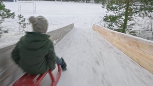 Kamera folgt Jungen beim Rodeln im Winter