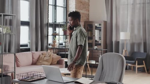 Adult Talking on Phone and Using Laptop in Office