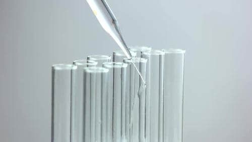 Wissenschaftlicher Forscher gießt transparente Flüssigkeit in Reagenzgläser