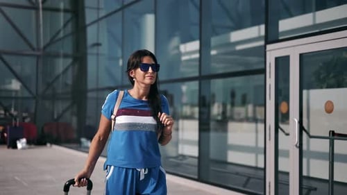 Brunette Female Passenger Walking Outdoor at International Airport Terminal Area Carrying Suitcase