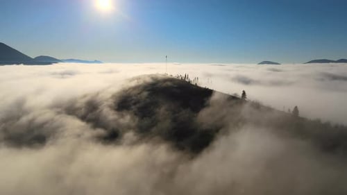 Aerial View of Colorful Sunrise Over White Dense Fog with Distant Dark Silhouettes of Mountain Hills