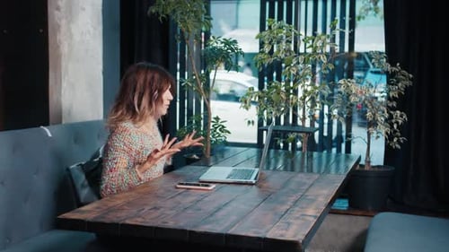 Happy Blogger Girl Talking on Laptop Sitting in Cafe