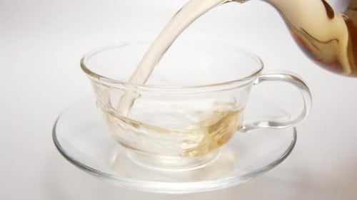 Heißer Tee fließt aus einer Teekanne zu einer Teetasse