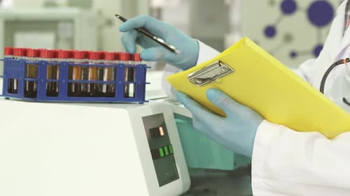 Eine Nahaufnahme der Hände des Laborassistenten, der die Daten über Reagenzgläser sorgfältig umschreibt