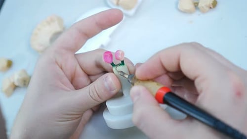 Dental Technician Working on Pink Tooth Mold