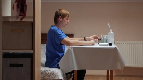 Young Adult Prepares and Takes Medication Indoors