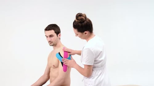 Woman Applies Kinesiology Tape to Man's Shoulder