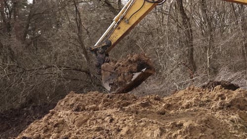Eimer mit Baggerladern, der auf der Baustelle Erde gräbt