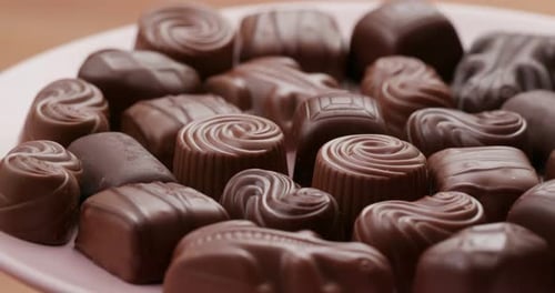 Assortment of Delicious Chocolate Candies on Pink Plate