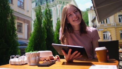 Young Woman Using Tablet Pc in a Cafe on a Summer Terrace