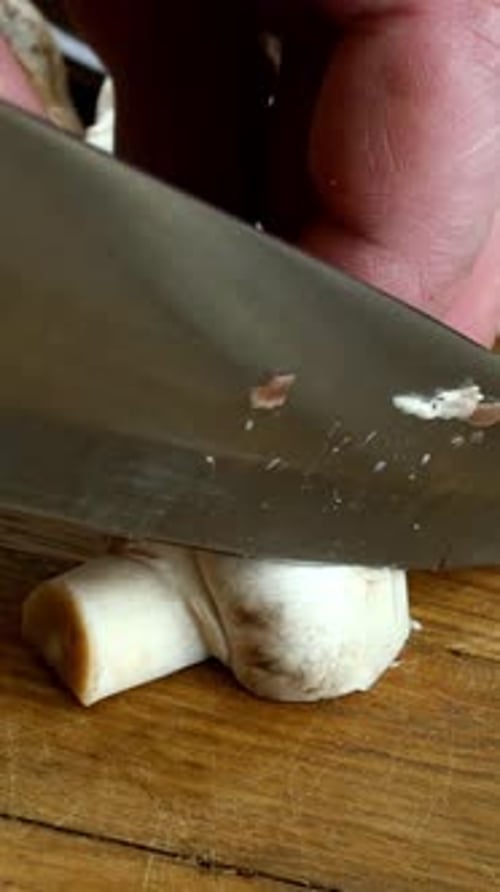 Mushroom Being Sliced on a Wooden Cutting Board