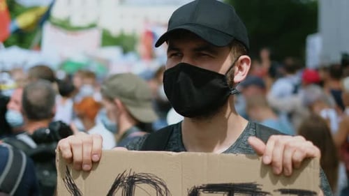 Young Adult Protester Holds Sign at Urban Protest
