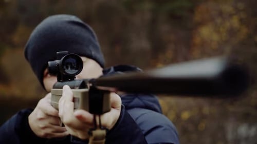 Cazador con rifle de caza. Primer plano de un joven cazador con rifle de caza apuntando en el bosque