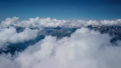 Luftflug durch Wolken über Berglandschaft
