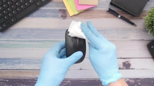 Cleaning Computer Mouse with Wipe on Wooden Desk